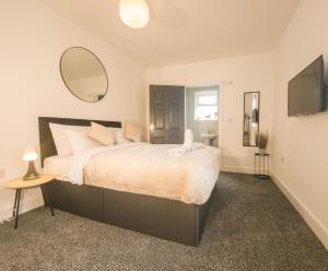 a bedroom with a large bed and a mirror at Principality Suites - Two Bed Apartment by Property Promise in Cardiff
