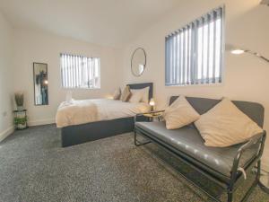 a bedroom with a bed and a couch at Principality Suites - Two Bed Apartment by Property Promise in Cardiff