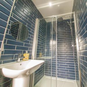 a blue tiled bathroom with a sink and a shower at Principality Suites - Two Bed Apartment by Property Promise in Cardiff