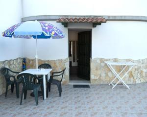 a table and chairs with an umbrella in front of a building at Appartamento sul mare in Su Forti