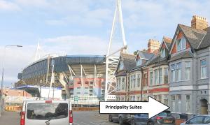 a white bus driving down a street in front of a stadium at Principality Suites - Two Bed Apartment by Property Promise in Cardiff
