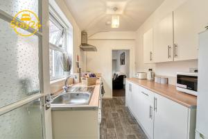 a kitchen with white cabinets and a sink at Cosy Carlton in Stoke on Trent