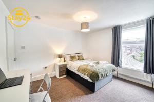特倫特河畔斯托克的住宿－Cosy Carlton，一间卧室配有一张床、一张书桌和一个窗户。