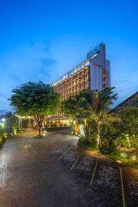 a hotel with palm trees in front of a building at THE 1O1 Bogor Suryakancana in Bogor