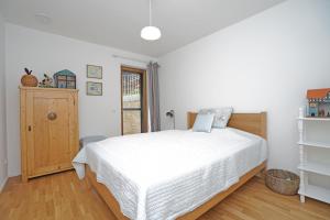 1 dormitorio con cama blanca y suelo de madera en Casa Montagna, en Oy-Mittelberg