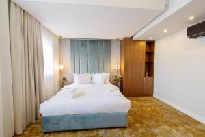 1 dormitorio con 1 cama grande con sábanas blancas en Yasu Luxury Rooms en Bucarest