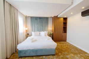 a bedroom with a large bed with white sheets at Yasu Luxury Rooms in Bucharest