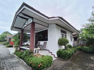 a small white house with a porch and stairs at THE NAIYANGHOUSE in Nai Yang Beach