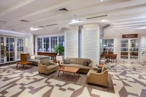 a lobby with couches chairs and tables and windows at THE 1O1 Bogor Suryakancana in Bogor