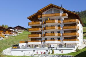un bâtiment avec des balcons sur le côté d'une montagne dans l'établissement Apartments Residenz Iris, à Loèche-les-Bains