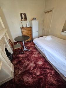 Schlafzimmer mit einem Bett, einem Tisch und einem Kühlschrank in der Unterkunft The 23 in London