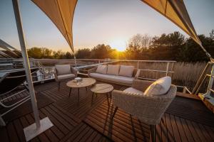 a deck with a couch and tables on a boat at Schwimmende Ferienhäuser auf dem See - Spreewald in Vetschau