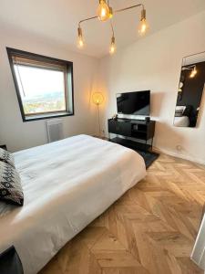 a bedroom with a large white bed and a television at Studio Esplanade bord du Lac in Aix-les-Bains