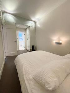 a bedroom with a large white bed and a mirror at Stylish apartment in the heart of Potts Point in Sydney