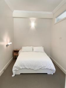 a white bedroom with a white bed and a window at Stylish apartment in the heart of Potts Point in Sydney