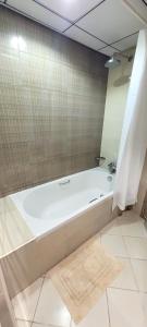 a white bath tub in a bathroom with a tile floor at Cozy 1BH Apt next to the sea! in Ajman 