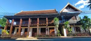 an old wooden house with a fence on a street at Ancient Luangprabang Hotel in Luang Prabang