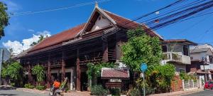 a woman riding a bike in front of a building at Ancient Luangprabang Hotel in Luang Prabang