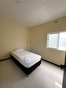 1 dormitorio con 1 cama en una habitación con ventana en Apartamentos sin fronteras, en Leticia