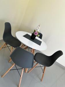 una mesa blanca con 2 sillas y un jarrón de flores en Apartamentos sin fronteras, en Leticia