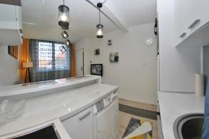 La cuisine est équipée d'un comptoir blanc et d'un réfrigérateur. dans l'établissement Cable Car Apartment Baščaršija, à Sarajevo