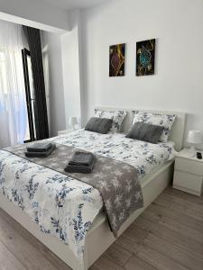 a white bedroom with a large bed with blue and white sheets at Angela Nordic apartment. in Suceava