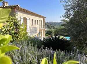 una casa con un jardín con flores púrpuras en Bastide d'Architecte en Pierre en Cagnes-sur-Mer