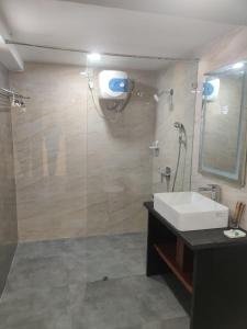a bathroom with a shower and a sink and a mirror at Grand Manor Suites in Hyderabad