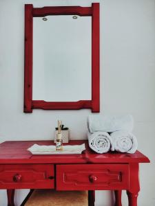 a red table with a mirror on a white wall at Rena's Rooms Μελίντα in Melínta
