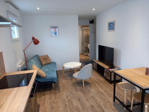 uma sala de estar com um sofá azul e uma televisão em Aux Portes de Brest em Le Relecq-Kerhuon