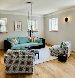 a living room with a green couch and two chairs at Traumurlaub auf dem Brandmanngut in Marquartstein