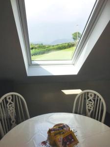 a white table and two chairs with a window at Mourne Views 2 Bed Apartment in Kilkeel