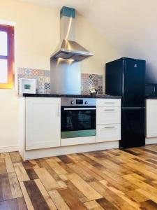 a kitchen with a stove and a black refrigerator at Mourne Views 2 Bed Apartment in Kilkeel
