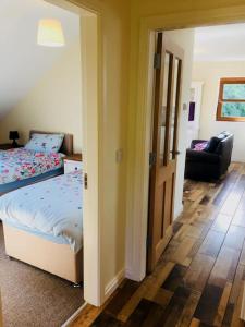 a bedroom with a bed and a hallway with a chair at Mourne Views 2 Bed Apartment in Kilkeel