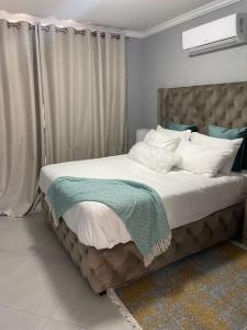 um quarto com uma cama grande com lençóis brancos e almofadas em Tranquility at Homely Escape em Phalaborwa