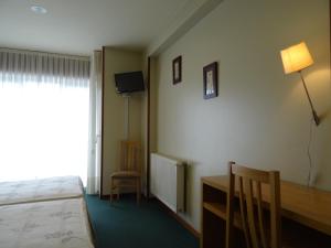 a hotel room with a bed and a desk and a window at Hotel Akelarre in Santiago de Compostela
