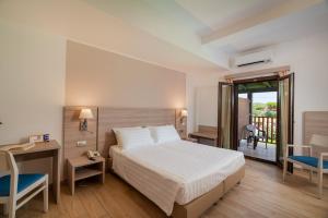 a hotel room with a bed and a desk and a balcony at Hotel Portoconte in Porto Conte