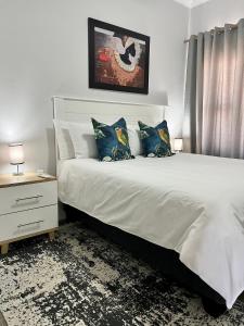 1 dormitorio con 1 cama blanca grande con almohadas azules en Sarona LoLa E206, en Gaborone