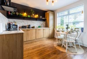 une cuisine avec des placards en bois et une table avec des chaises dans l'établissement KIRA Beach House, Large luxury 2 bedroom apartment, à Hove