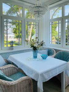 een eetkamer met een witte tafel met stoelen en een kroonluchter bij Villa Svanen am Meer in Timmendorfer Strand