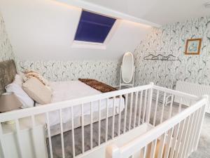 a white crib in a room with wallpaper at Through the Looking Glass in Ripon