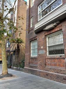 a brick building with a tree in front of it at Stylish apartment in the heart of Potts Point in Sydney