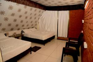 a bedroom with two beds and a chair and a window at Rama Hills Unity Resort in Lāchharas