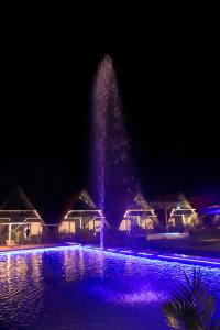 una fontana di fronte a un edificio con luci viola di Rama Hills Unity Resort a Lāchharas