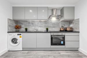a kitchen with white cabinets and a washer and dryer at Serviced Ensuite Room Finsbury Park London N19 in London