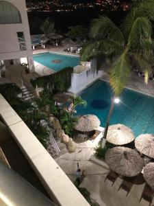 an overhead view of a swimming pool with umbrellas at Apartamento Torres gemelas in Acapulco