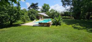 una piscina con panchina e ombrellone in un cortile di Au séchoir à Tabac a Bergerac