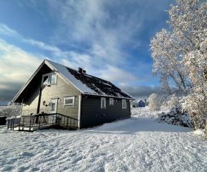 a house with snow on the ground next to a house at Cozy house in an Arctic village 