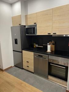 a kitchen with stainless steel appliances and wooden cabinets at Francisca City House in Vila Nova de Gaia