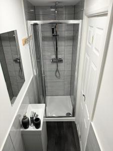 a small bathroom with a shower and a sink at Twickenham Apartments by Charles in Teddington